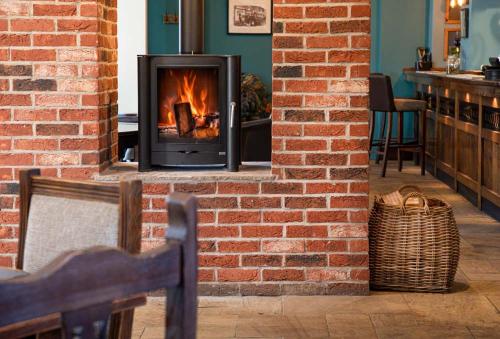 a fireplace in a brick wall with a stove at Red Lion Inn Wybunbury in Wybunbury