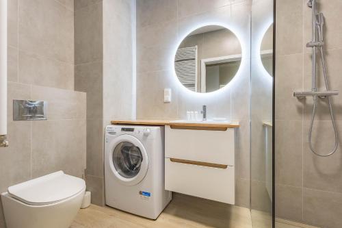 a bathroom with a washing machine and a mirror at Miedza Apartament - Targówek, Metro Trocka in Warsaw