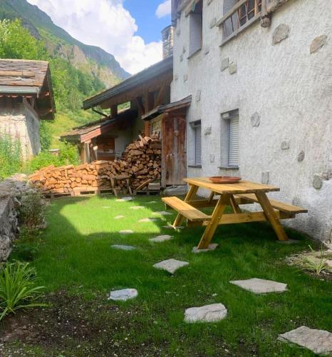 une table de pique-nique devant un bâtiment avec un tas de bûches dans l'établissement Serac Appartement au coeur de la vanoise, à Champagny-en-Vanoise