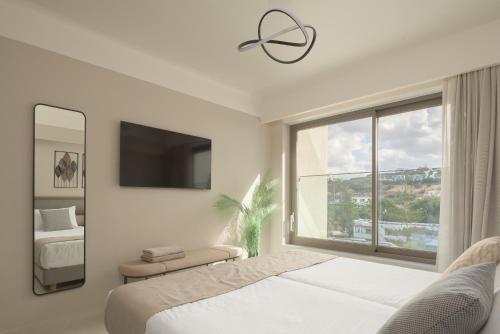 a white bedroom with a bed and a window at Creta Star Hotel - Adults Only in Skaleta