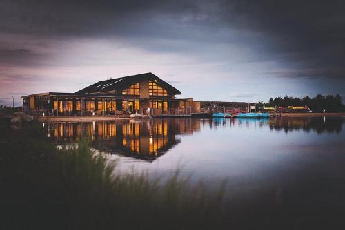 a large building on a lake with the lights on at Miarlo Lodge Rydal Haven Lakeland in Flookburgh