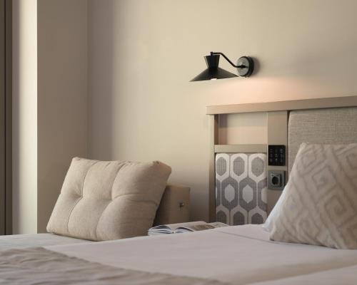 a bedroom with a bed with white sheets and a lamp at Creta Star Hotel - Adults Only in Skaleta