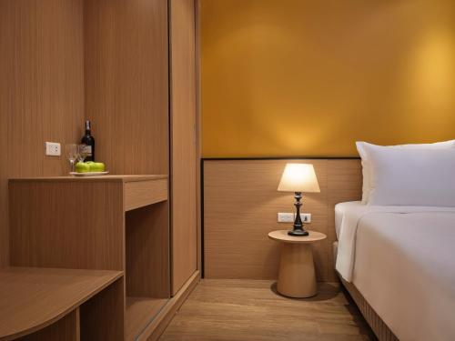a bedroom with a bed and a table with a lamp at Minasi Grand Hotel in Hanoi