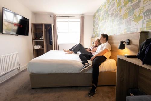 two people sitting on a bed in a bedroom at The Camden Street Hotel in Dublin