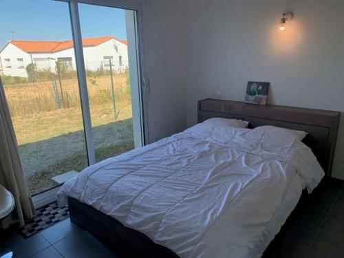 a bed in a bedroom with a large window at La Grisot de la mer Saint Hilaire in Saint-Hilaire-de-Riez