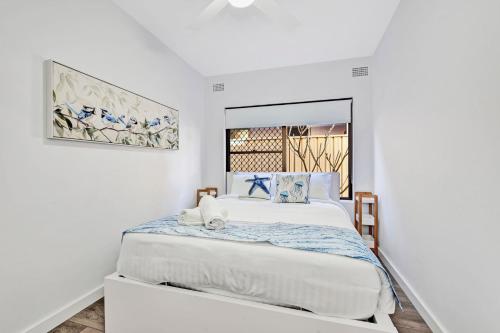 Dormitorio blanco con cama grande y espejo en Waterfront Reflections, en Corlette