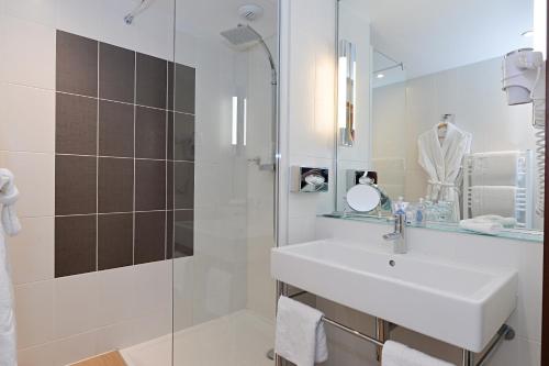 a white bathroom with a sink and a shower at Hôtel Mercure Toulon La Seyne-Sur-Mer in La Seyne-sur-Mer