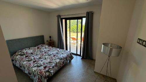 - une chambre avec un lit et une porte donnant sur une terrasse dans l'établissement Un air de paradis à Corbara, à Corbara