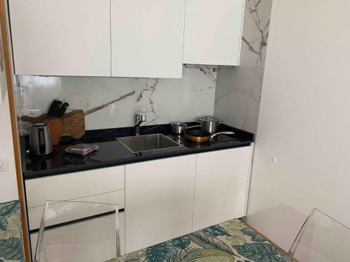 a kitchen with white cabinets and a sink at Maison Eglantine in Mezzana