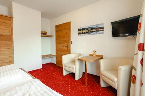 a hotel room with a bed and a table and chairs at Glautschhof in Weissensee