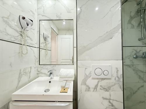 une salle de bain blanche avec un lavabo et un miroir dans l'établissement 65-FRENCH CANCAN ST DENIS, à Paris