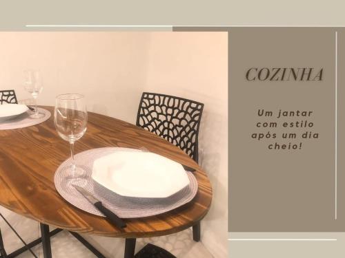 a wooden table with a plate and a glass of wine at Apto Executivo Confortável in Teófilo Otoni