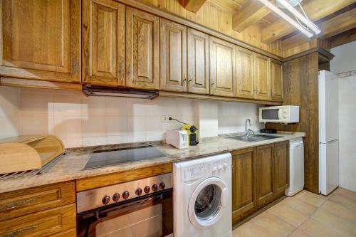 a kitchen with wooden cabinets and a washer and dryer at Arties Luxury Apartments - parking a pie de pistas Val de Ruda in Arties