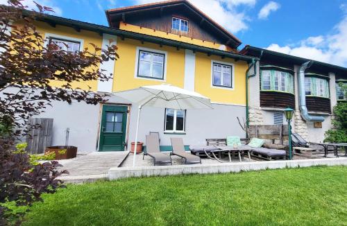 a yellow and white house with chairs and an umbrella at Almliesl Gruppenhaus PUCH-625 in Puchenstuben