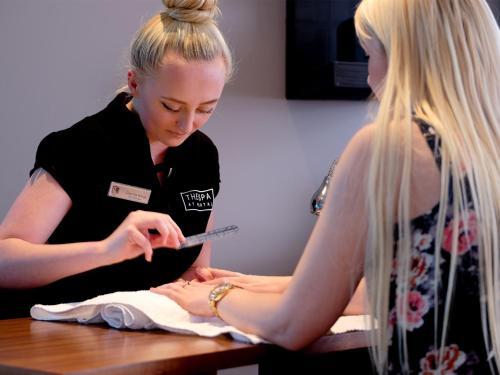 a woman getting a tattoo on a persons arm at Macdonald Portal Hotel, Spa & Golf Resort in Tarporley