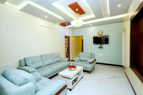 a living room with blue couches and a tv at Cozy Heaven in Ooty