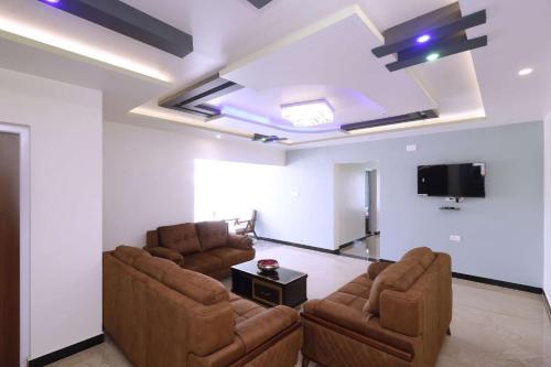 a living room with two couches and a flat screen tv at Cozy Heaven in Ooty