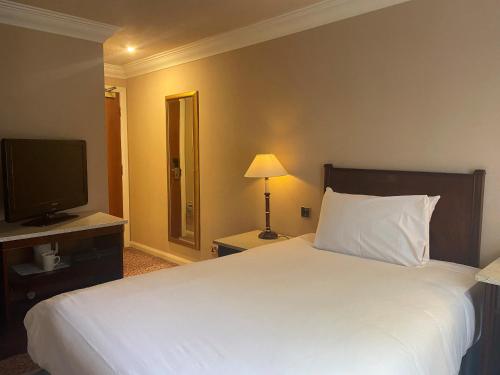 a hotel room with a bed and a television at Shrigley Hall Hotel in Macclesfield