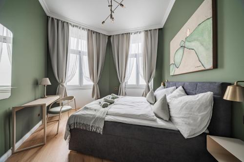 a bedroom with a bed and a desk and windows at HOME1 - District Twelve Boutique Hostel in Vienna