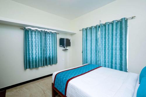 a bedroom with a bed with blue curtains and a tv at Cozy Heaven in Ooty