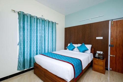 a bedroom with a large bed with blue curtains at Cozy Heaven in Ooty