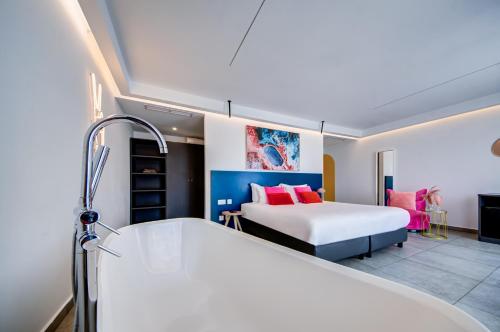 a bedroom with a bed and a tub in a room at Flamingo Hotel Malta in St Julian's