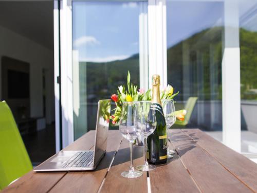 a table with a bottle of wine and a laptop and glasses at Villa Irene in Trenčianske Teplice