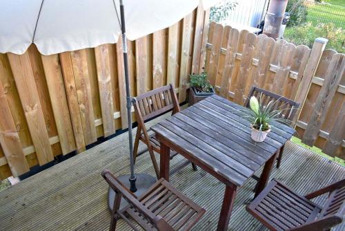 een houten tafel en stoelen met een parasol op een terras bij Lütt Hus an de See Ferienwohnung in Niendorf
