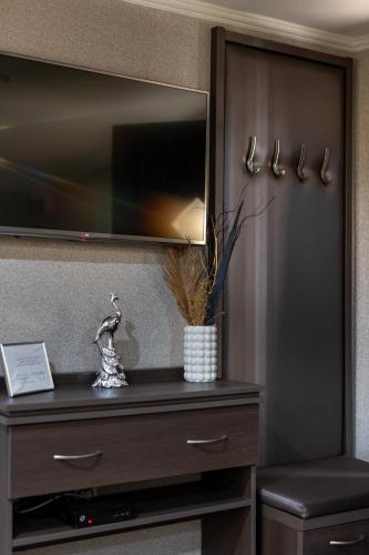 a dresser with a television on a wall at Royal Apartments Hotel Kecskemét in Kecskemét