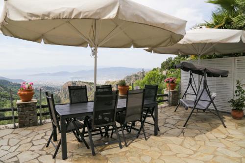a table and chairs under an umbrella on a patio at Villa Blanca Koukourava in Makrinitsa