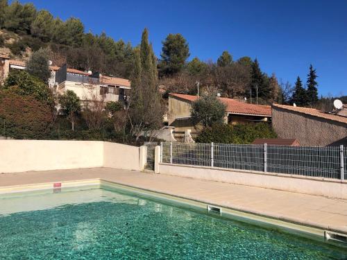 une piscine d'eau avec une clôture et des bâtiments dans l'établissement Le Soleil - Mazet 33, à Saint-Martin-de-Brômes