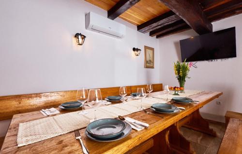 a wooden table with plates and wine glasses on it at Villa 77 by Villas Guide in Sisak