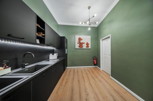 a kitchen with green and black cabinets and a wooden floor at HOME1 - District Twelve Boutique Hostel in Vienna