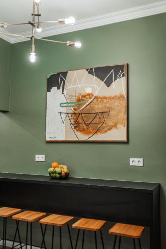 a painting hanging on a green wall with stools at HOME1 - District Twelve Boutique Hostel in Vienna