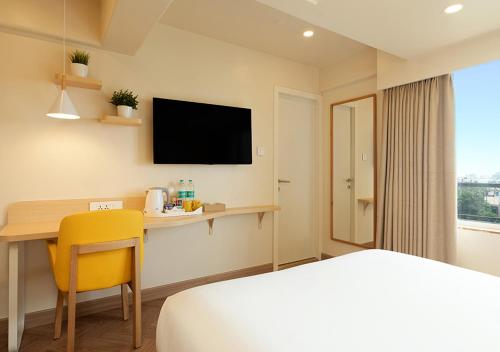 a hotel room with a bed and a desk and a tv at Bloom Hub WEH Andheri in Mumbai