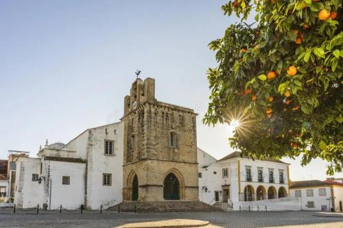 an old stone building with a tower on a street at Simply House in Faro