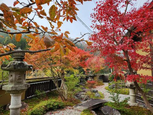 a garden in autumn with a stone lantern and a tree at Miyama Resort Kayabuki-tei - Matsuba's Inn in Nantan city