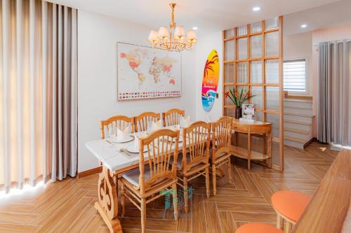 a dining room with a table and chairs and a surfboard at DT Retreat - Biệt thự nguyên căn - 3 Phòng ngủ - Novaworld Phan Thiết in Phan Thiet