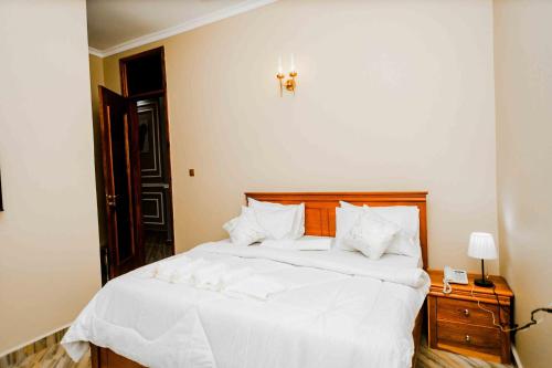 a bedroom with a white bed with a wooden headboard at Joy Inn Hotel in Dar es Salaam