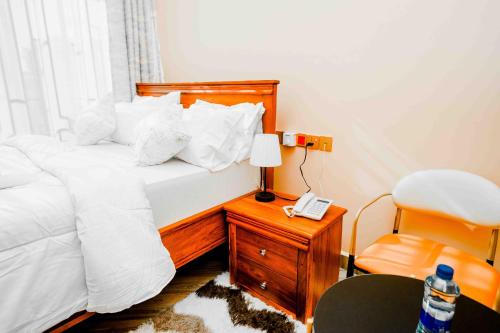 a bedroom with a bed with a phone and a chair at Joy Inn Hotel in Dar es Salaam