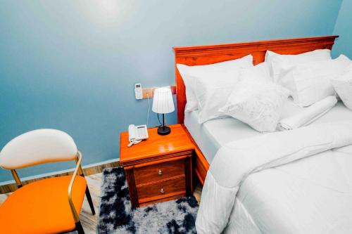 a bedroom with a bed and a desk with a lamp and a chair at Joy Inn Hotel in Dar es Salaam