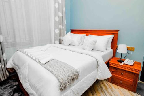 a bedroom with a white bed with a phone on a night stand at Joy Inn Hotel in Dar es Salaam