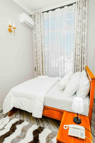 a bedroom with a bed with a window and a telephone at Joy Inn Hotel in Dar es Salaam