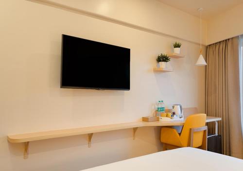 a room with a television on a wall with a desk at Bloom Hub WEH Andheri in Mumbai