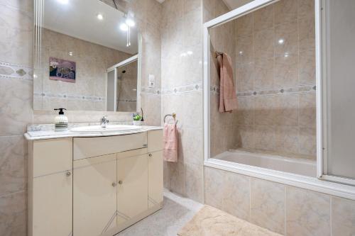 a bathroom with a sink and a shower and a tub at Apartamentos El Compromiso in Caspe