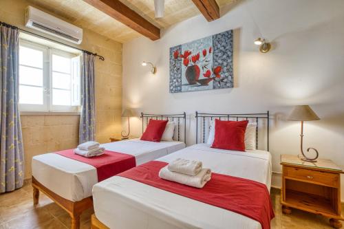 a bedroom with two beds with red and white sheets at Karmnu Holiday Farmhouse in Għasri