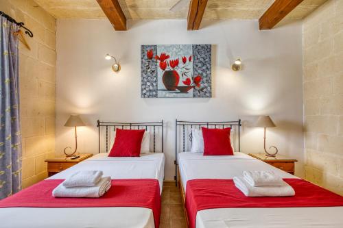 two beds in a room with red pillows at Karmnu Holiday Farmhouse in Għasri