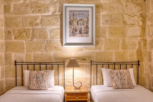 two beds in a room with a stone wall at Karmnu Holiday Farmhouse in Għasri