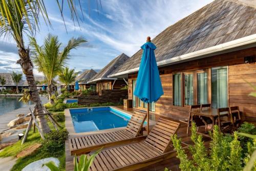 a house with a pool and a blue umbrella at Buffalo Island Resort & Adventure Park in Ban Pa Mak (1)