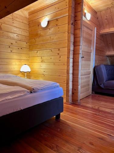 a bedroom with a bed and a door and a chair at Domki letniskowe Azalia in Ustronie Morskie